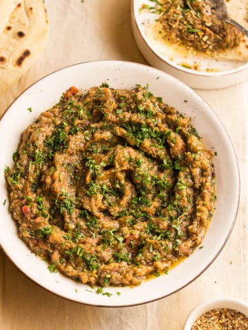 Zaalouk in a white bowl served with flat bread and dukkah.