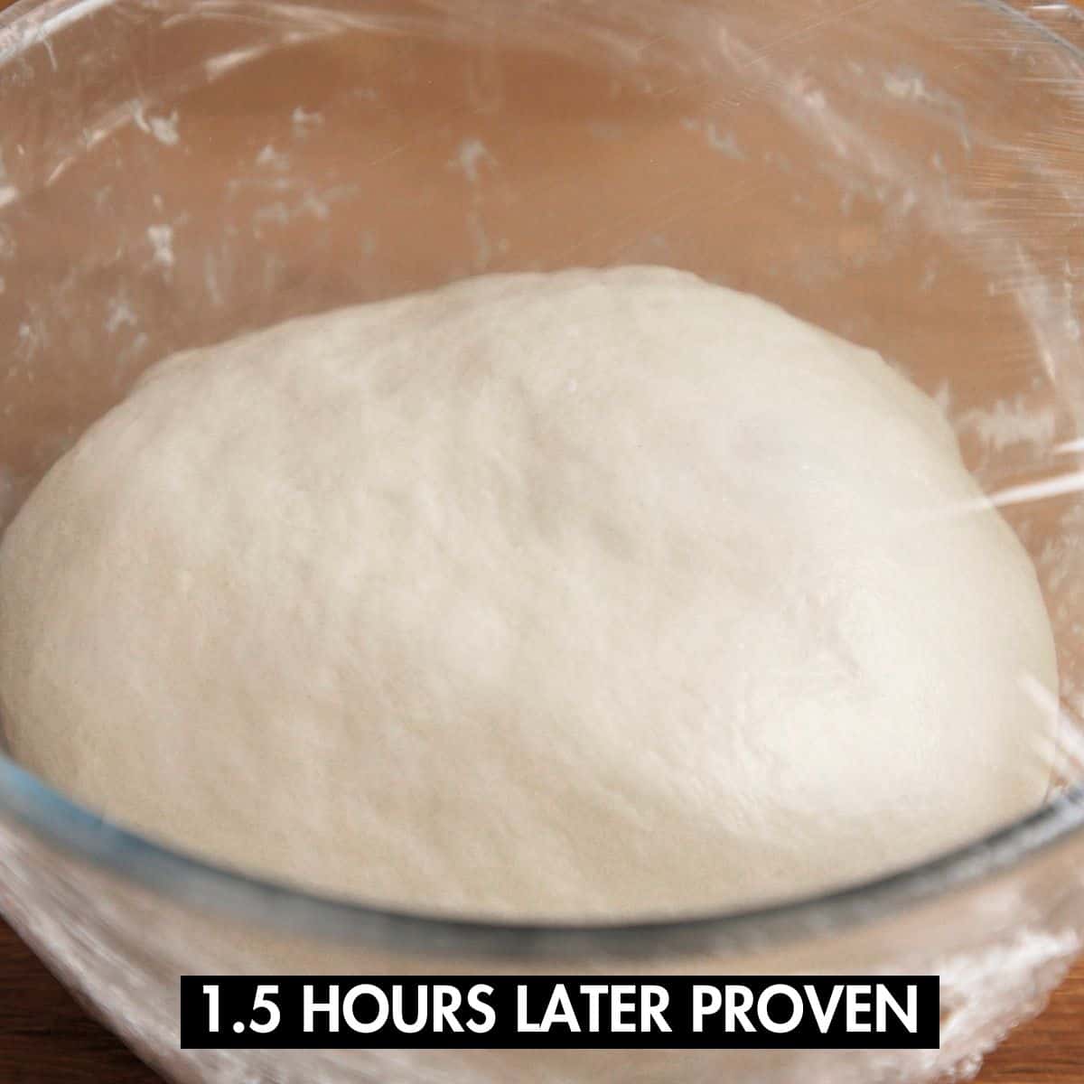 Risen naan dough in a glass bowl.