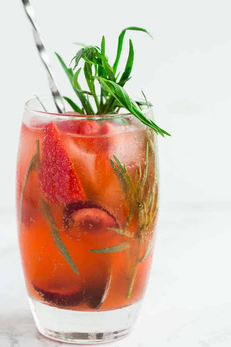 strawberry soda in glass with fresh berries and tarragon.