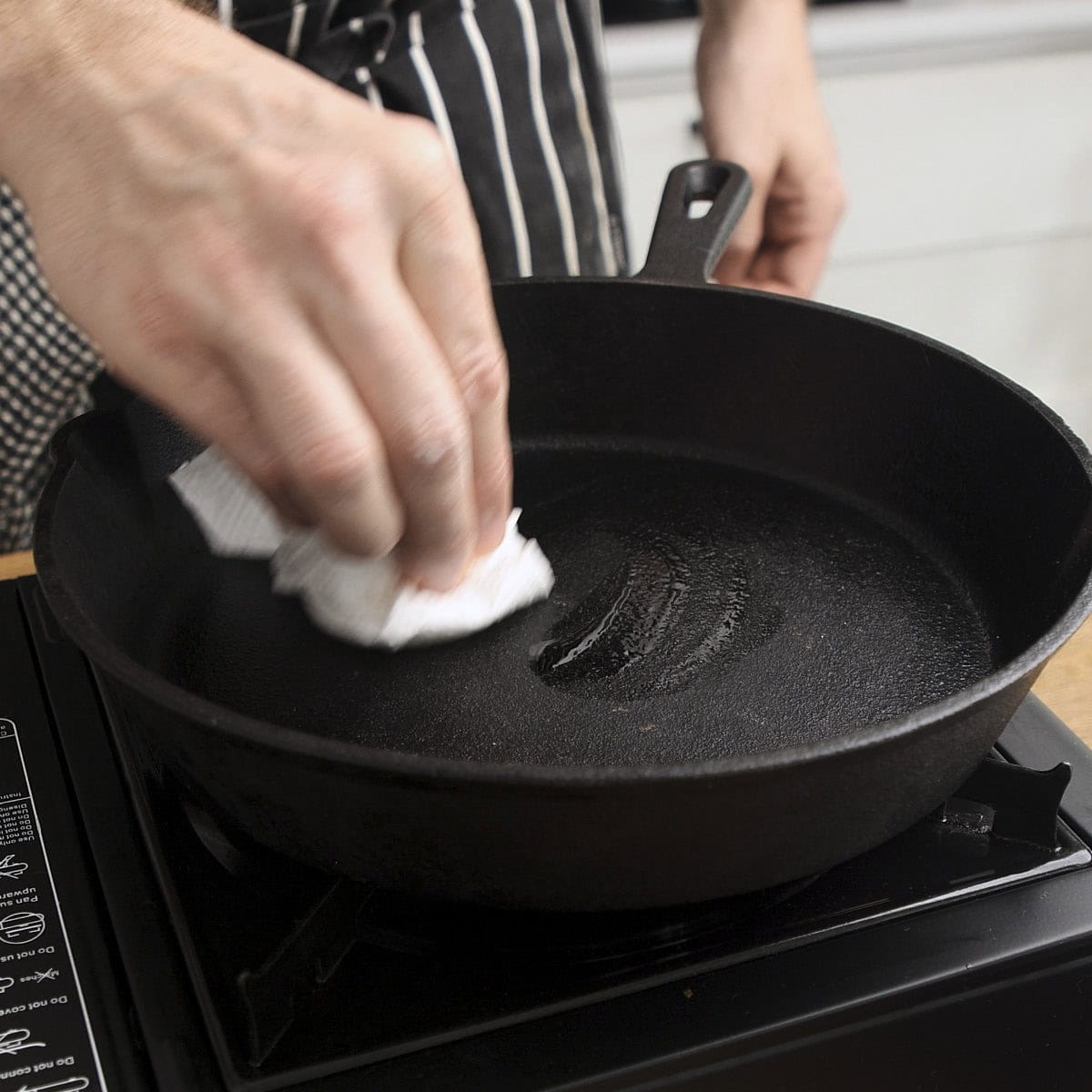 Oiling a skillet with a touch of oil and removing excess oil with paper towel.