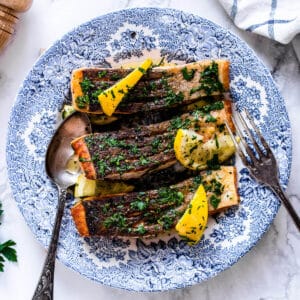 seared salmon fillet on a blue plate with lemon and parsley