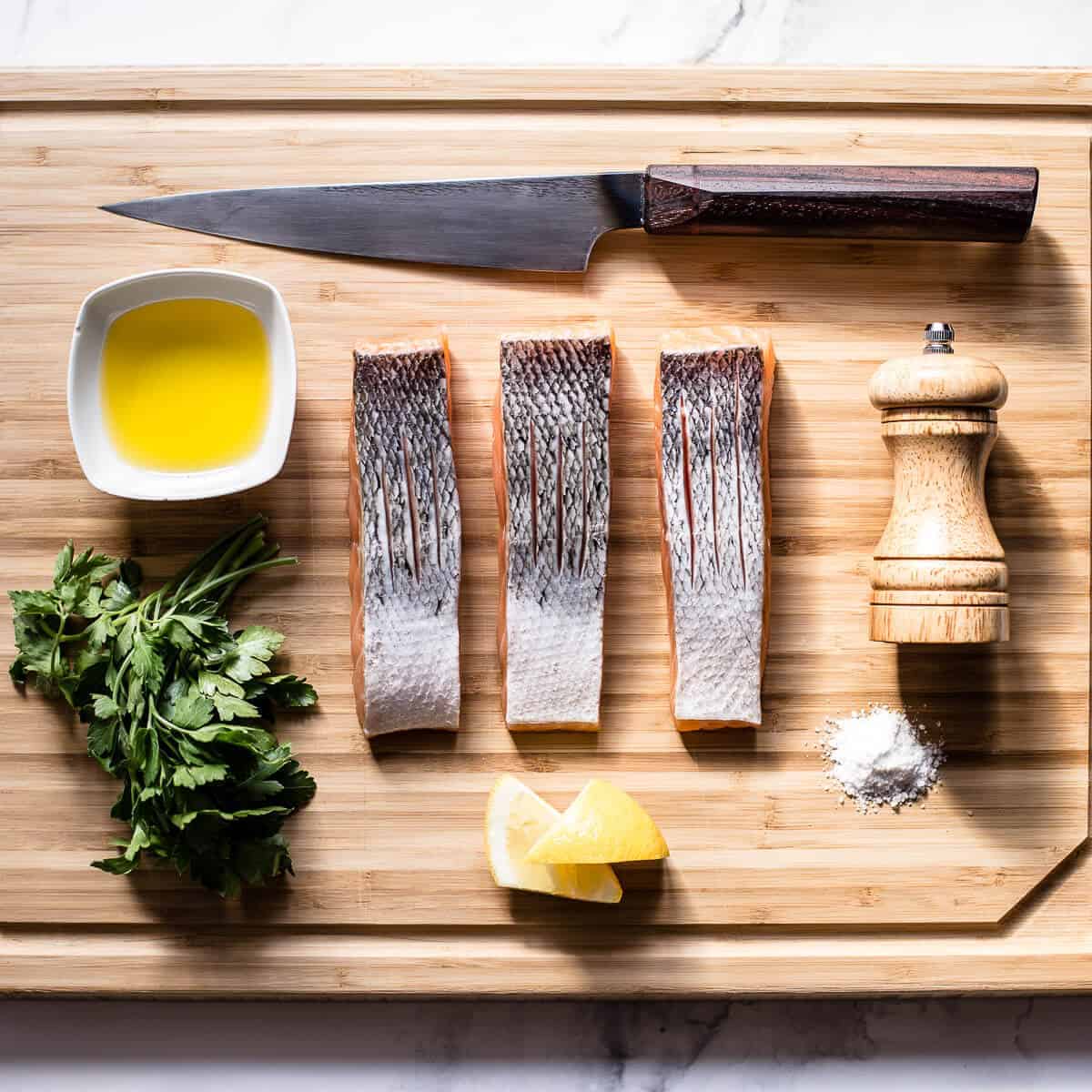 ingredients needed to pan fry salmon on a wooden board.