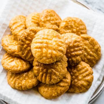 Parmesan sablé cookies stacked on top of each other on a white plate.