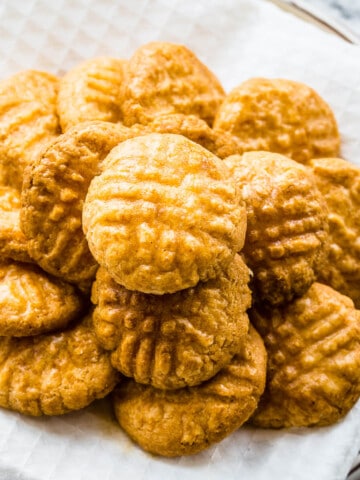 Parmesan sablé cookies stacked on top of each other on a white plate.