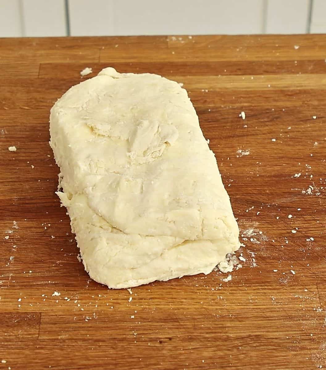 Pastry dough folded into thirds like a letter on floured marble surface