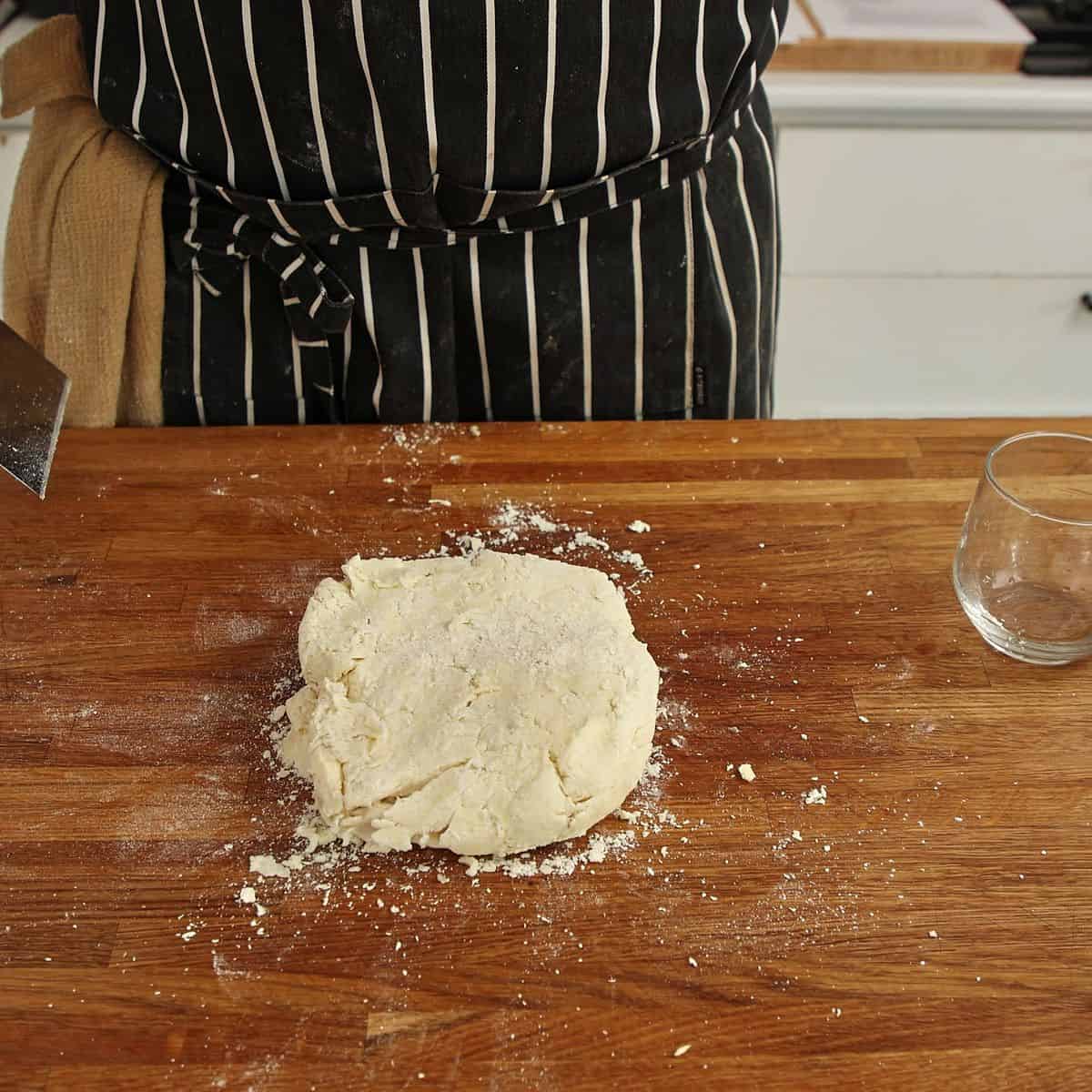 Rough shaggy pastry dough pressed into loose rectangle on floured surface with visible butter chunks