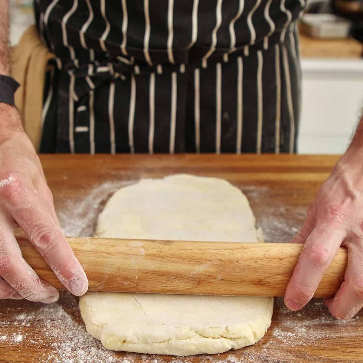 Pastry rolled into rectangle approximately 40 x 20 cm with visible butter chunks throughout dough.