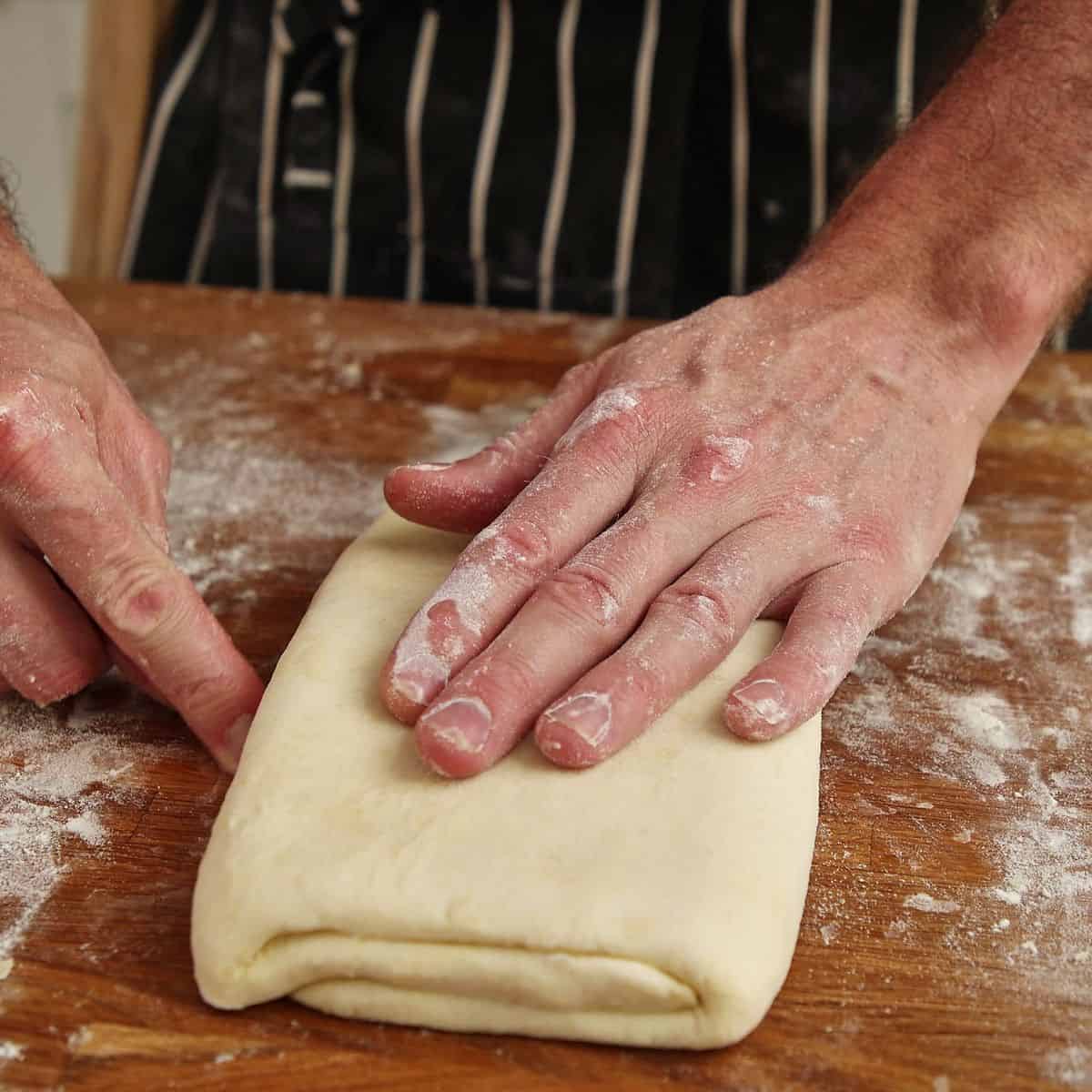 Pastry turned 90 degrees after first fold showing open folded edges facing toward camera