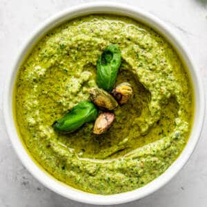 Pistachio pesto in a white bowl with basil.