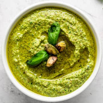Pistachio pesto in a white bowl with basil.
