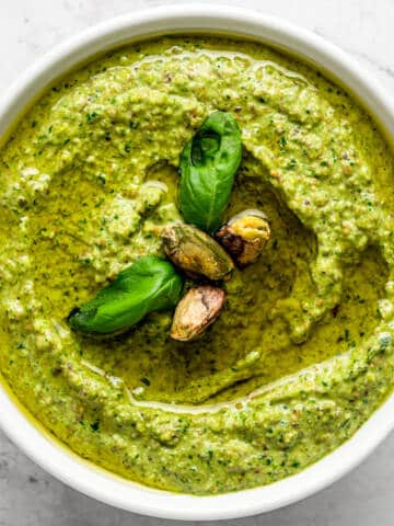 Pistachio pesto in a white bowl with basil.