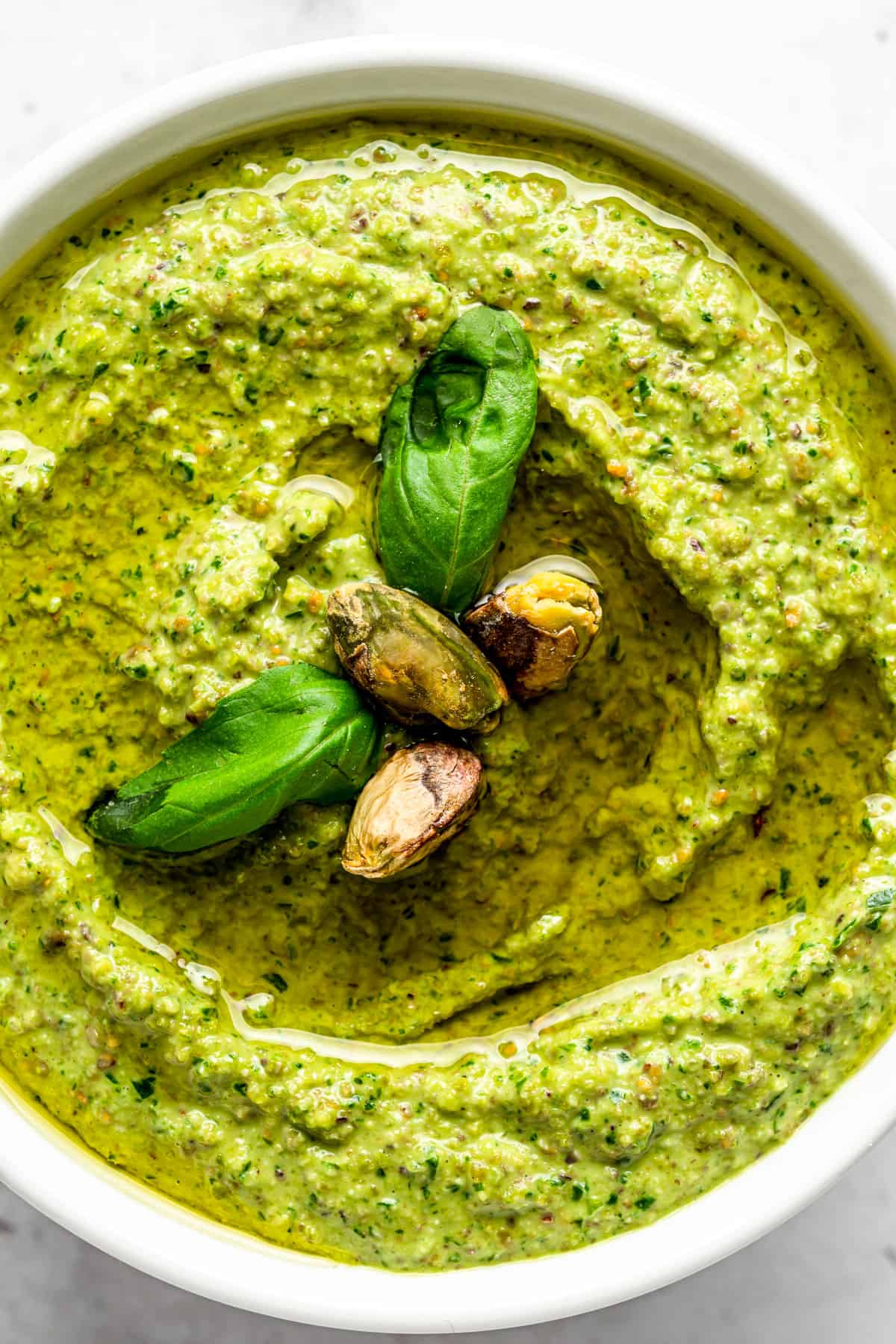 Pistachio pesto in a white bowl with basil.