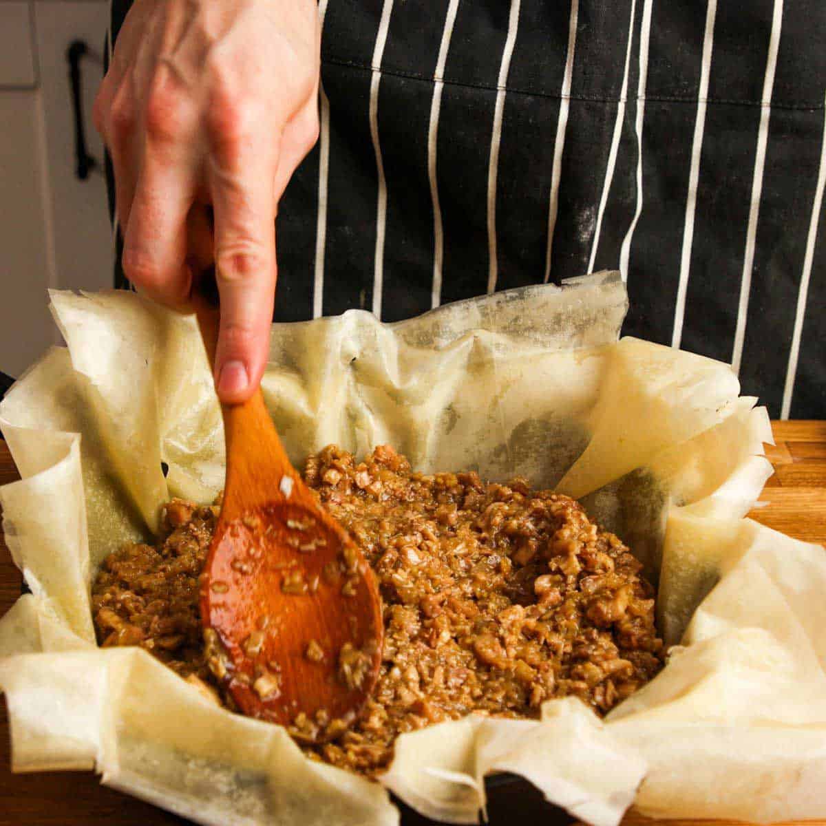 Adding chicken filling to pan lined with phyllo.