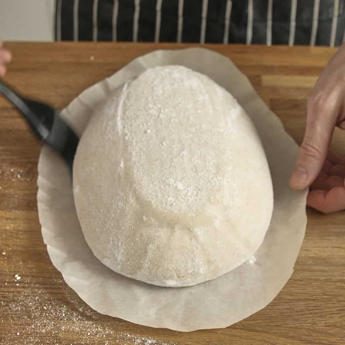 Brushing excess flour from a loaf before baking.