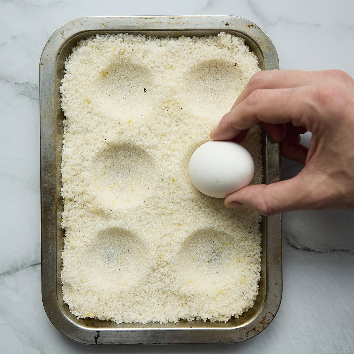 Preparing indentations in salt cure on a tray.