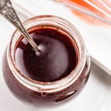 pomegranate vinaigrette dressing in a glass jar with metal spoon