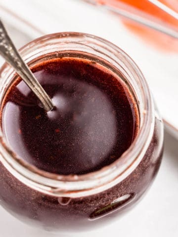 pomegranate vinaigrette dressing in a glass jar with metal spoon