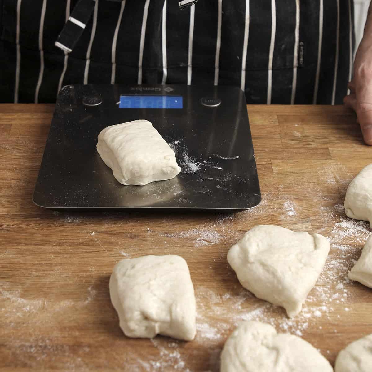 Weighing equal sized pieces of dough with scales.