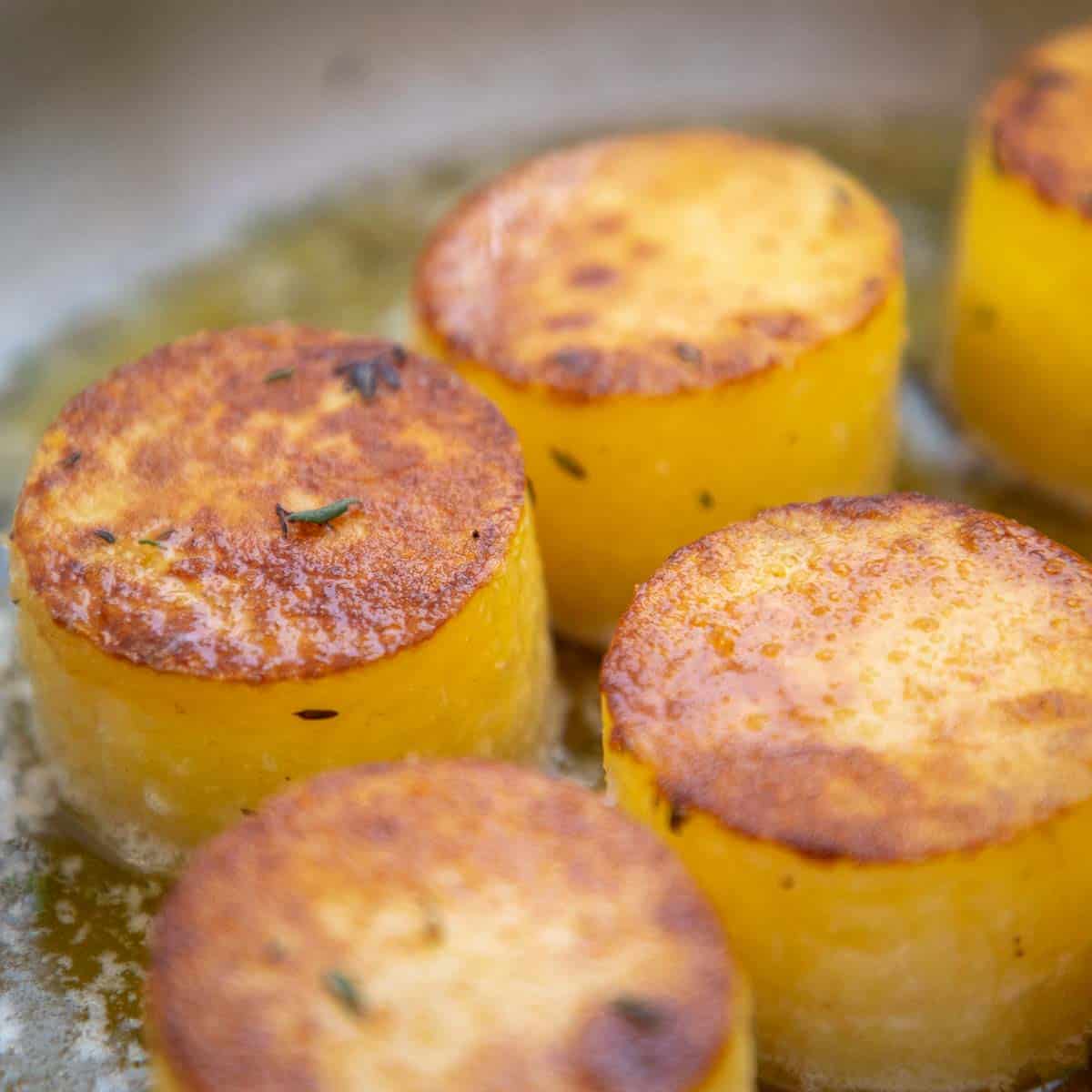 Stock added to fondant potatoes in a pan.