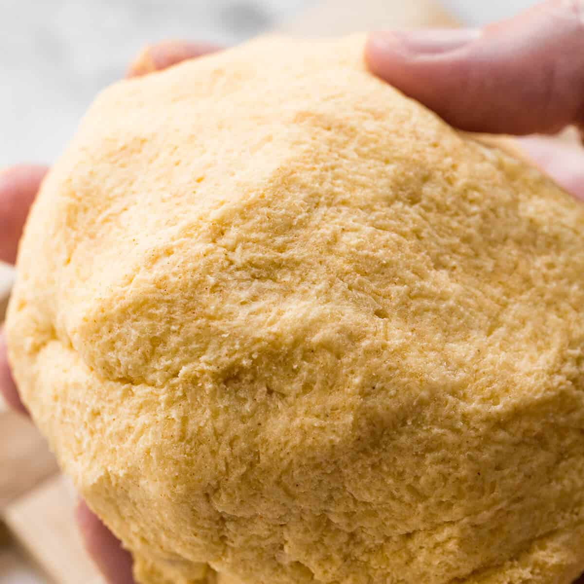 A smooth, homogeneous ball of parmesan shortbread dough wrapped and ready to be chilled.