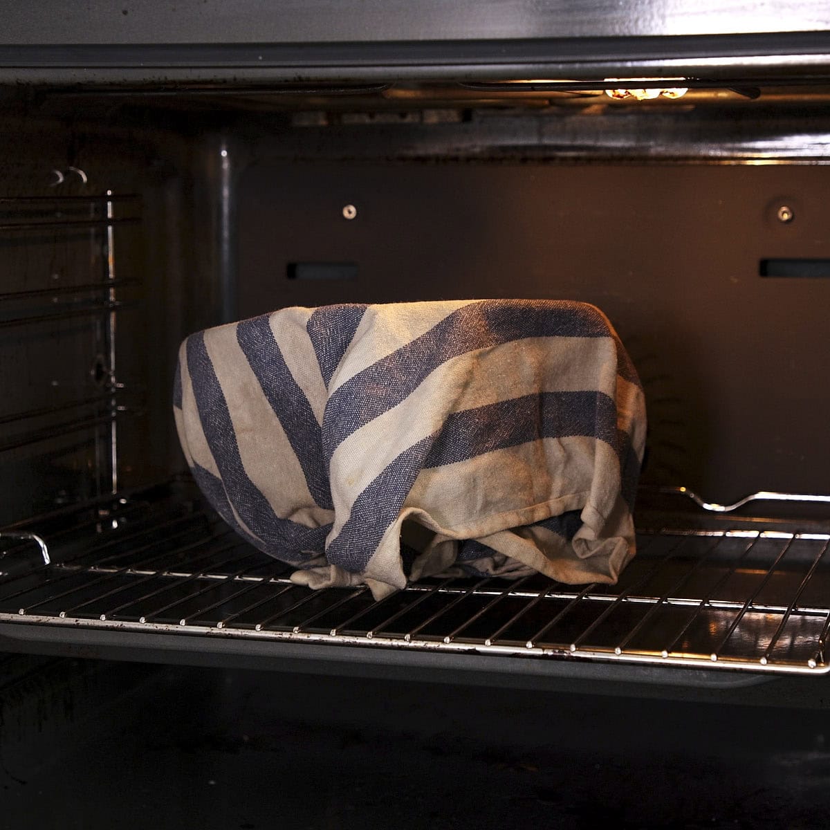 Bowl cover in damp cloth in oven with only the light turned on.