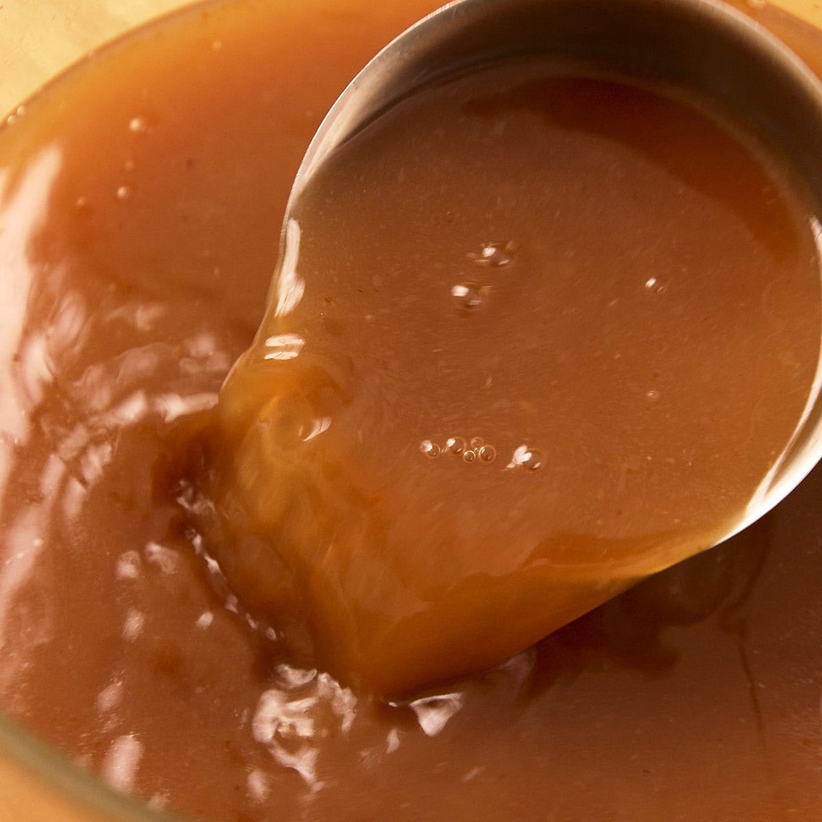 Clear beef stock after straining in a ladle.