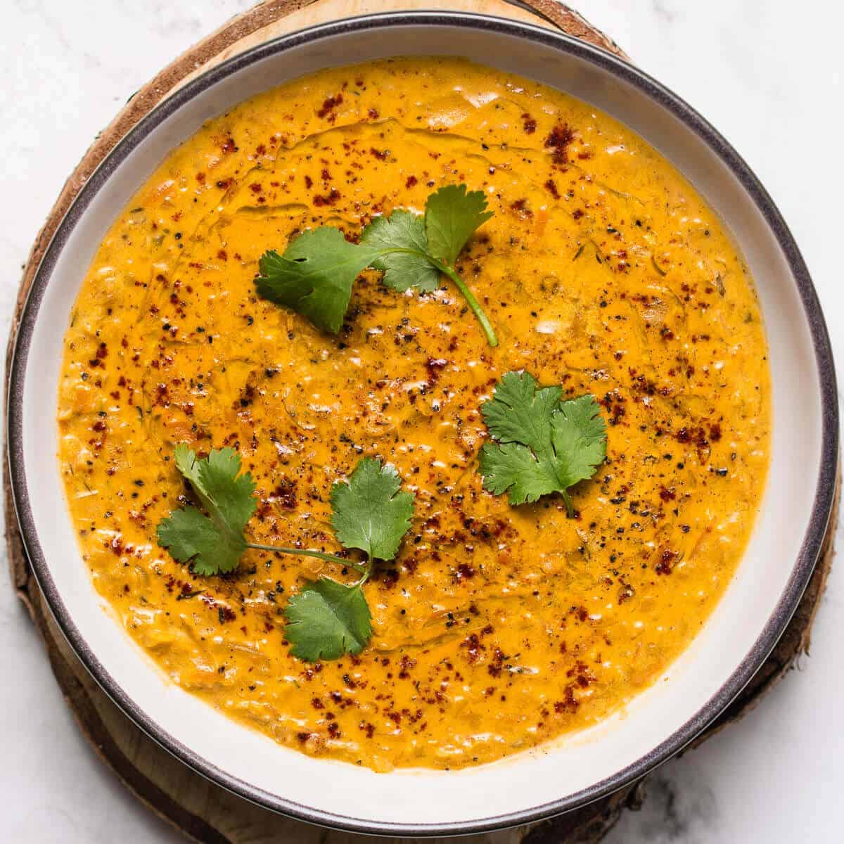 red lentil soup in white bowl with cilantro and smoked paprika