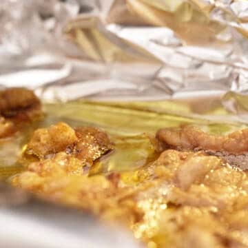 Rendering chicken fat from chicken skins on a foil lined oven tray.