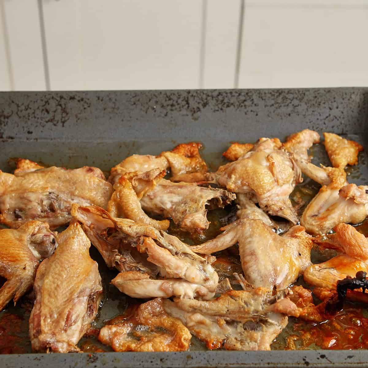 Roasted chicken bones and wings turned deep amber on a tray.
