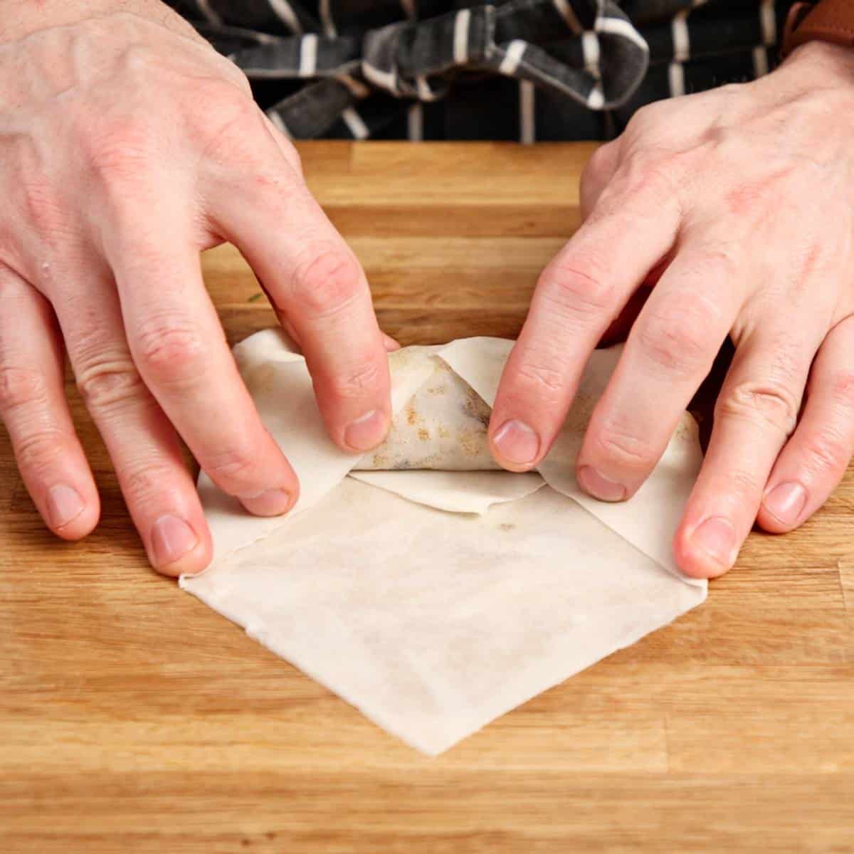 Rolling a spring roll on a wooden board.