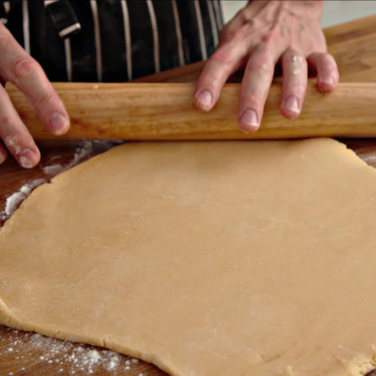 Rolling out pastry on wooden board.