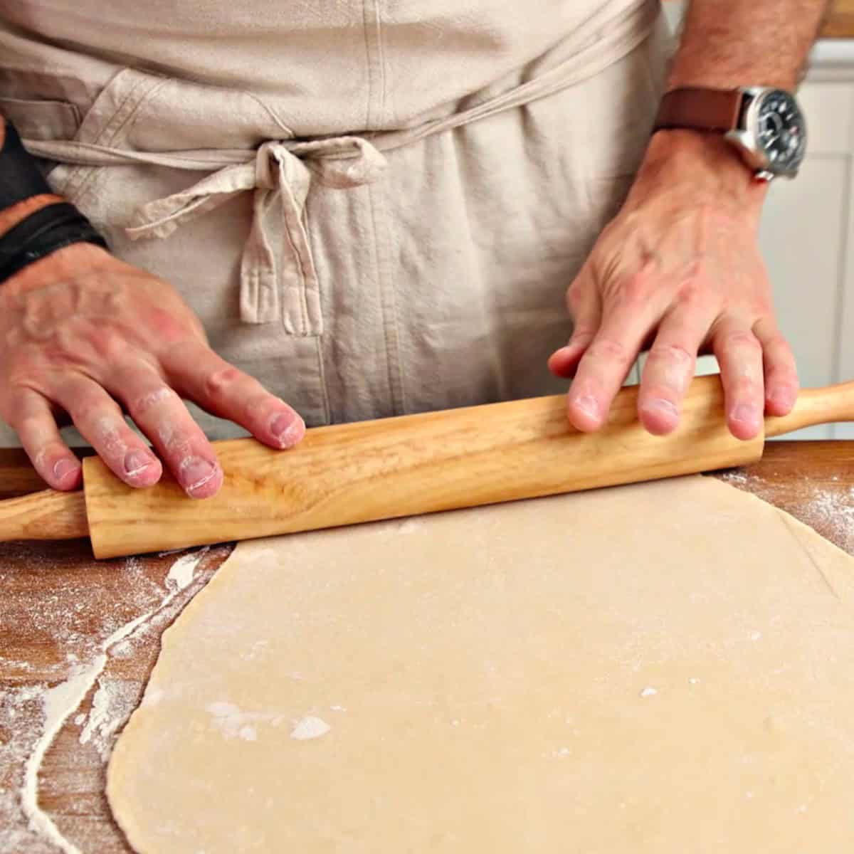 Rolling pelmeni dough with a rolling pin.