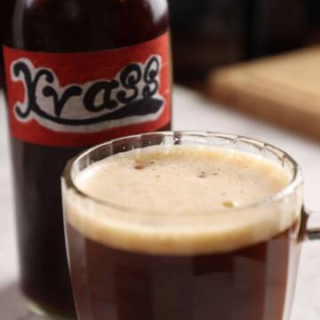 Black bread kvass in a beer glass on white table.