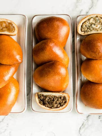 Individual apple, meat and cabbage Russian piroshki on marble background.