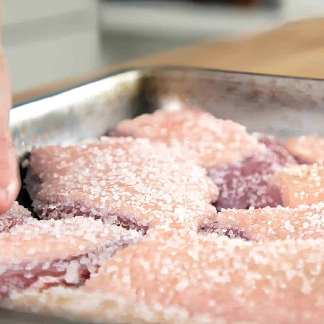 Duck breasts salting and curing on a metal tray.