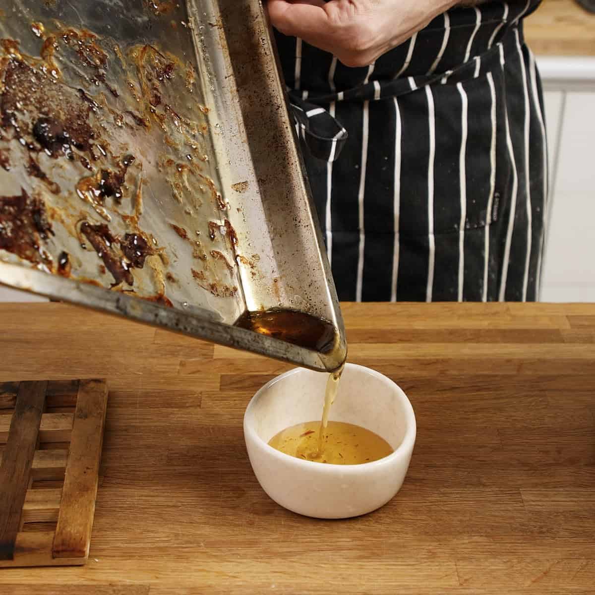 Pouring rendered beef fat into a bowl.