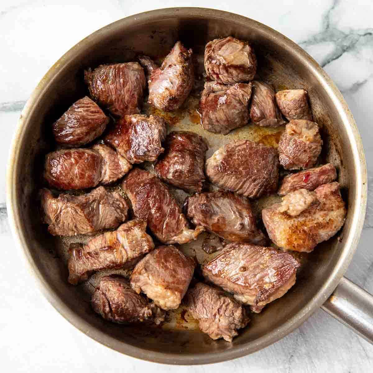 Meat searing in a pan.
