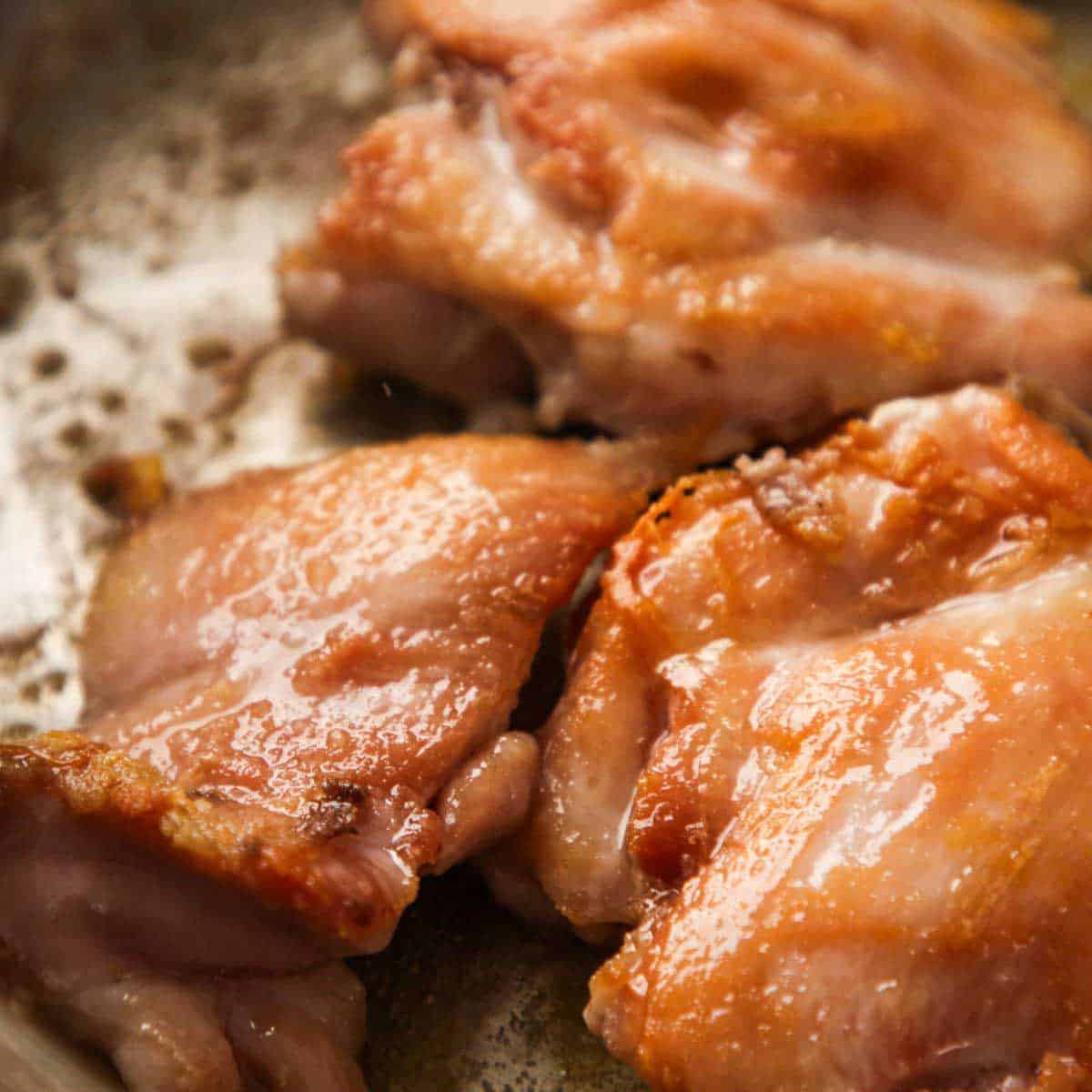 Searing chicken thighs in a pan.