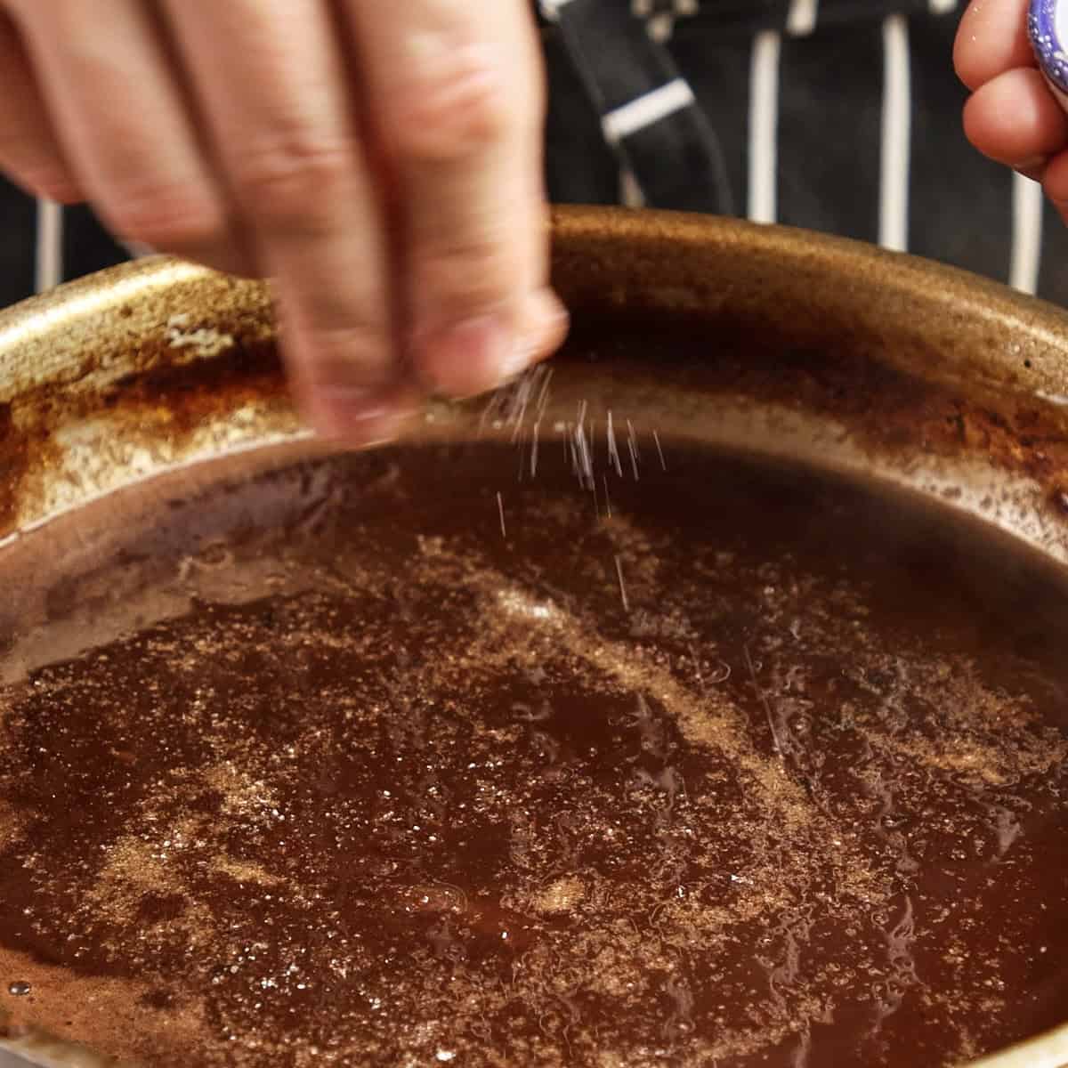 Seasoning onion gravy with salt.