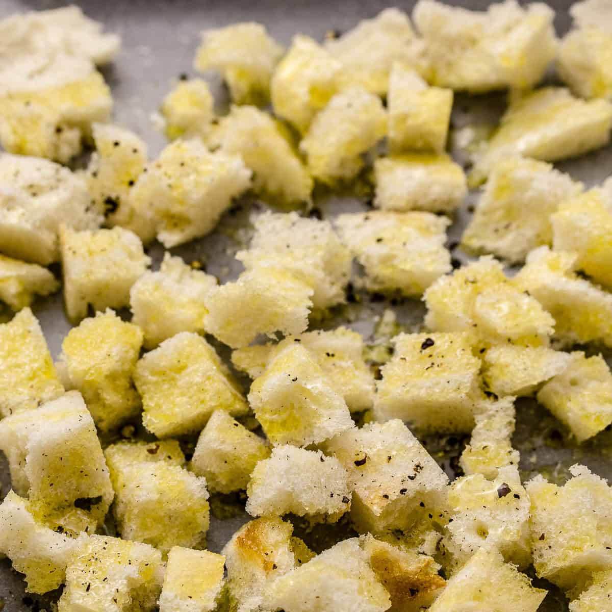Seasoned brioche croutons on a tray before going into the oven.
