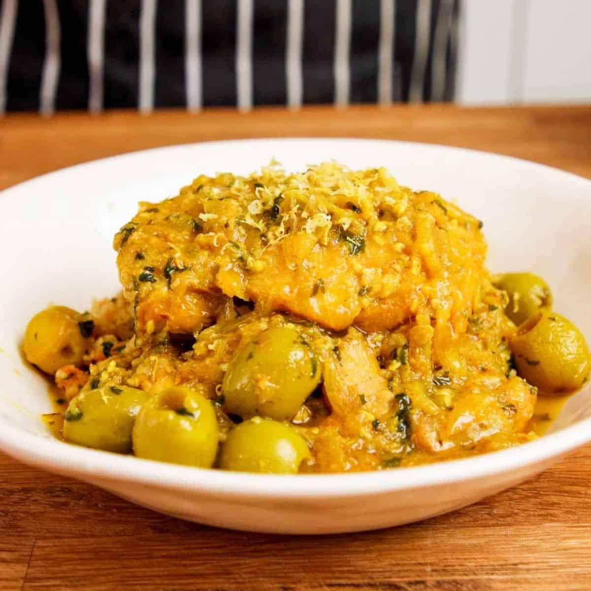 Serving chicken over couscous in a white bowl.