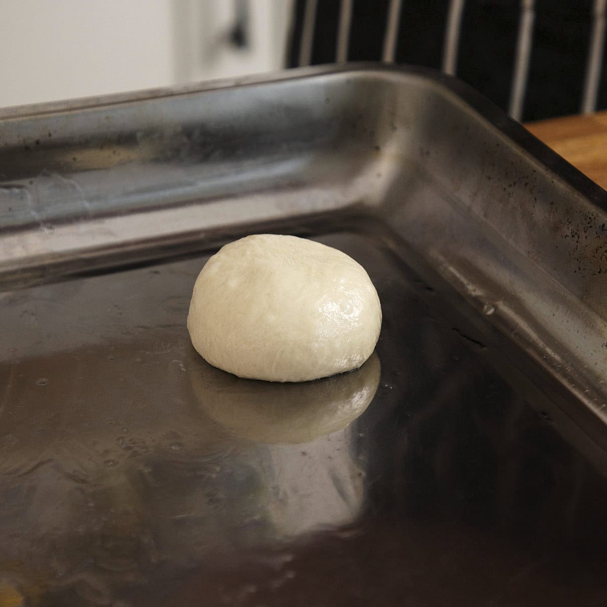Shaped naan dough on a oiled tray.