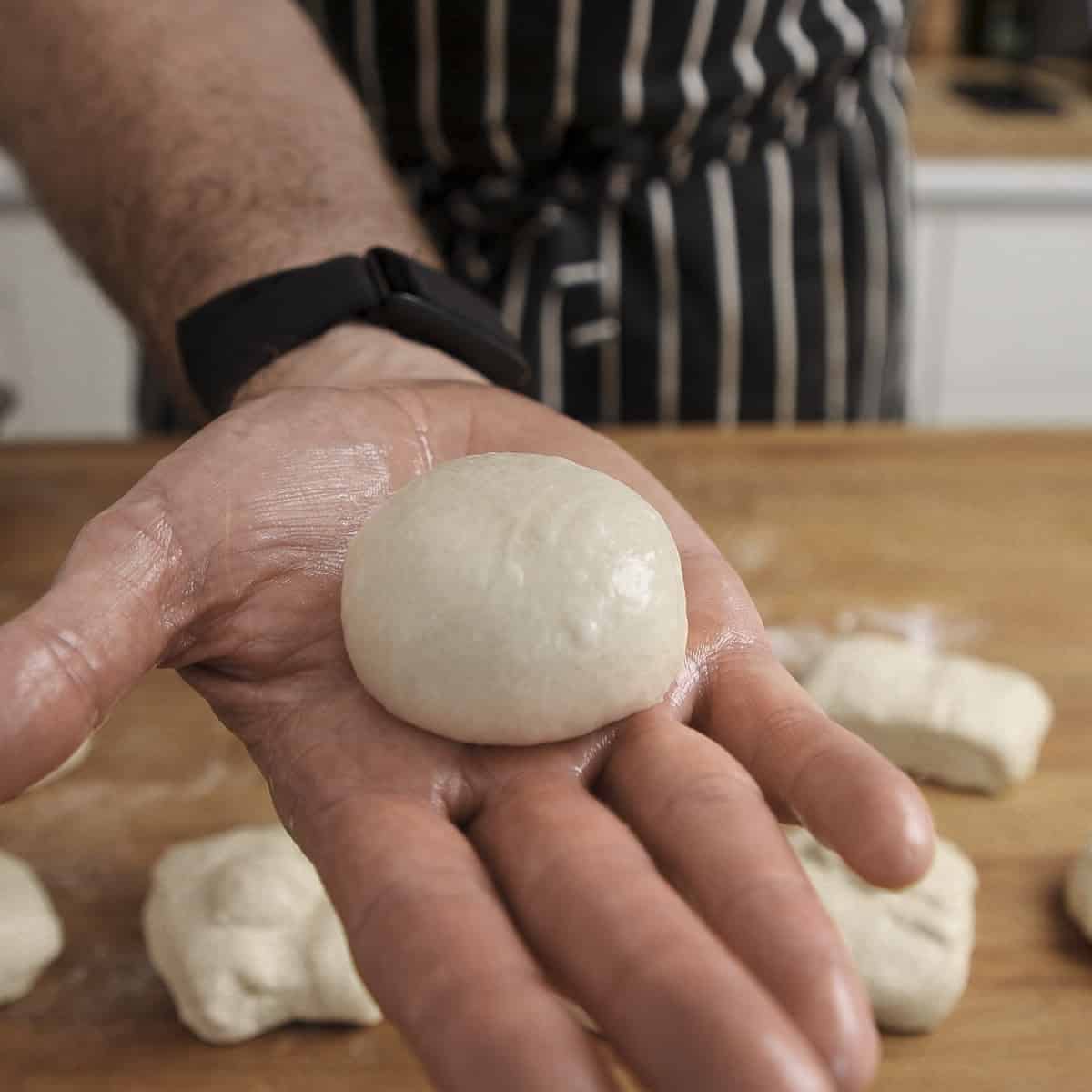 Shaped naan dough ball on hand.