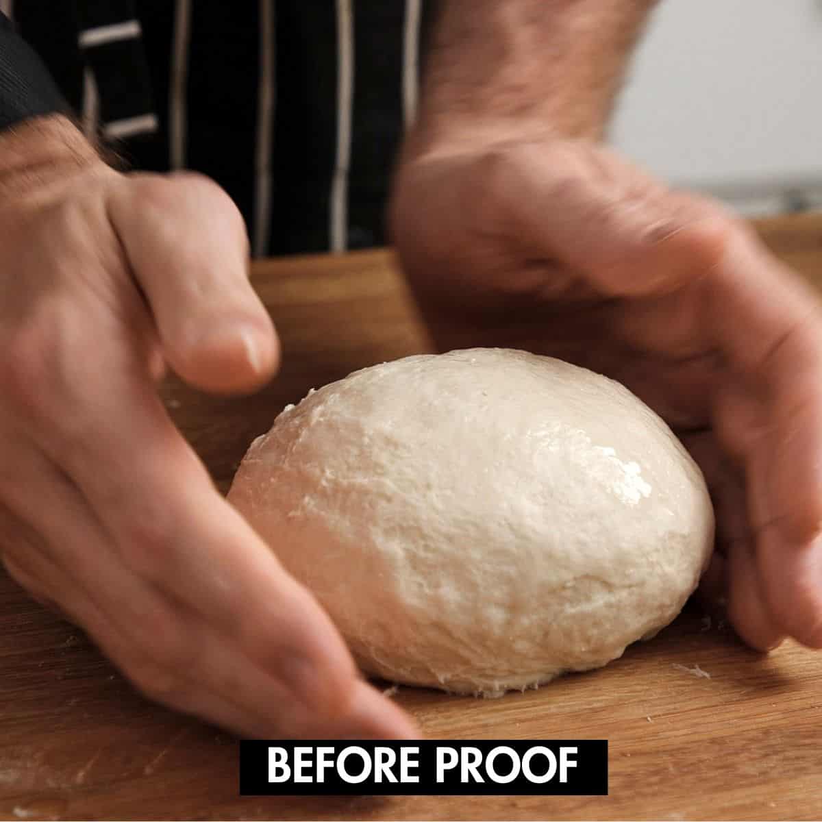 Shaping dough into a ball on a wooden surface.