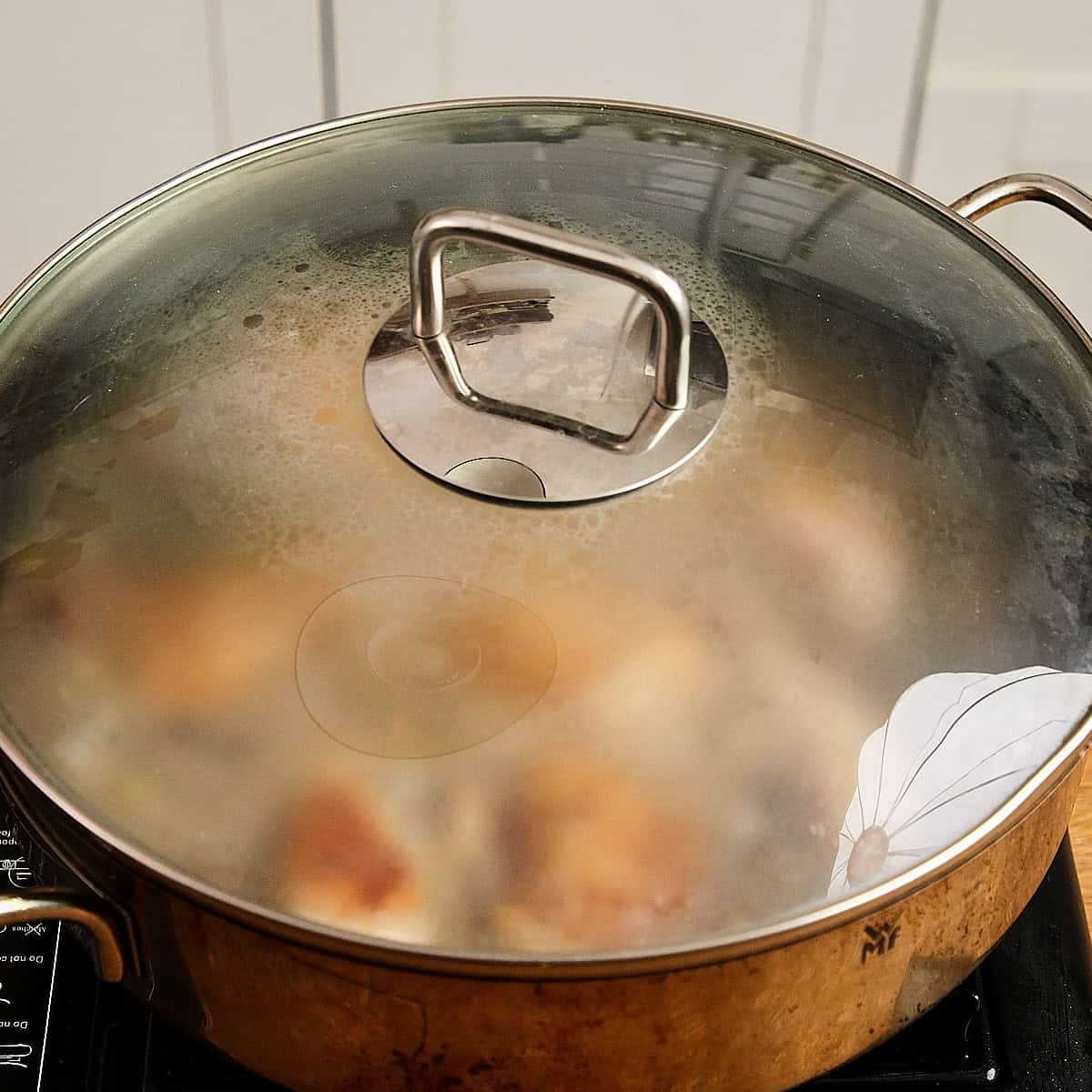 Stewing chicken a pan closed with a lid on low heat.