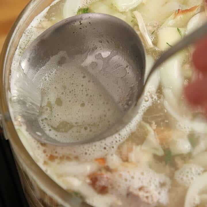 Skimming impurities from simmering chicken stock.