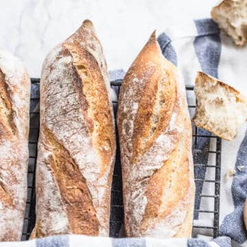 baguette bread on wire rack with striped kitchen towel