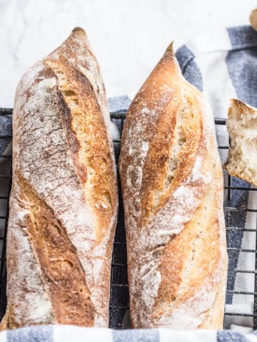 baguette bread on wire rack with striped kitchen towel