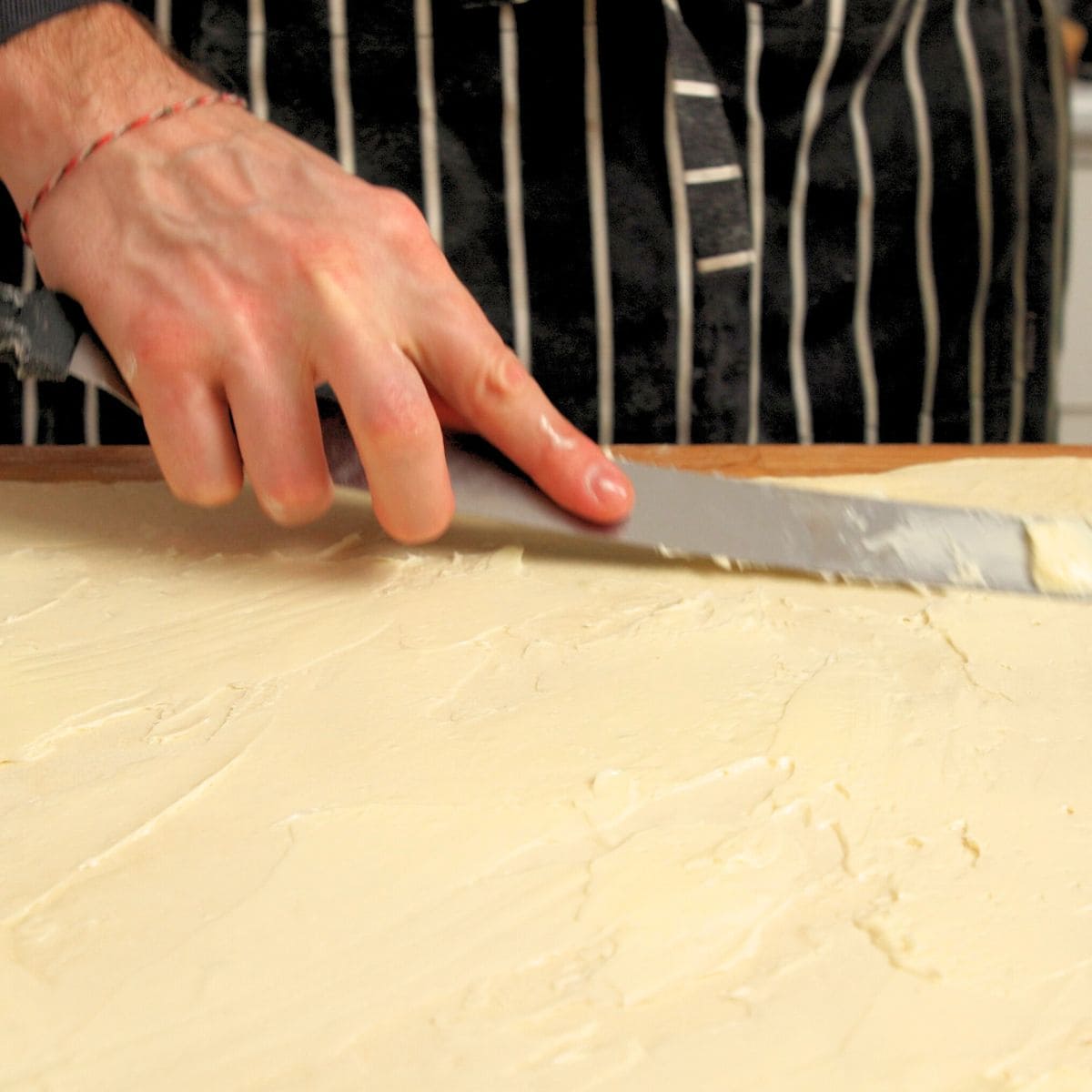 Spreading butter onto thinly rolled out dough.
