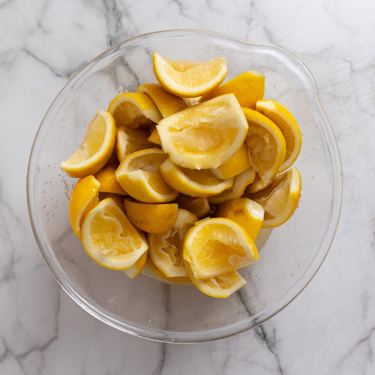 Bruised salted lemons in a glass bowl.